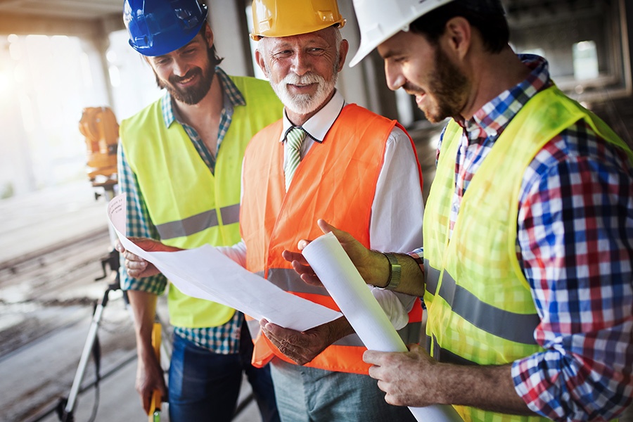 Specialized Business Insurance - Engineers and Construction Site Manager Conversing and Dealing with Blueprints and Construction Plans